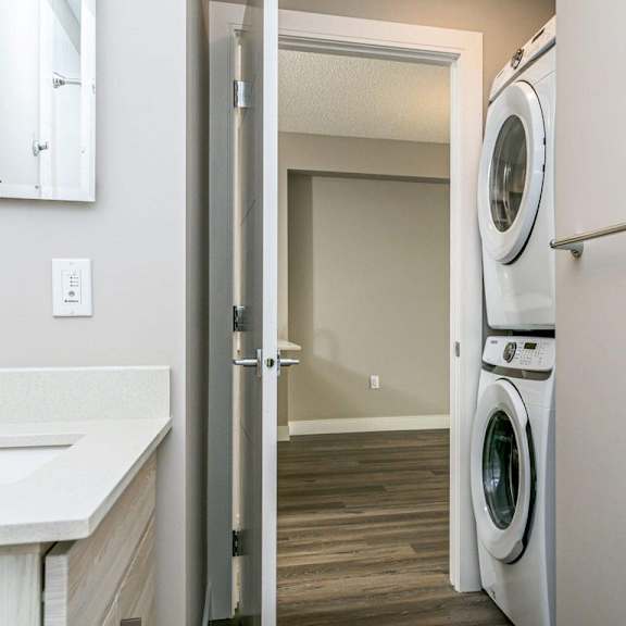 a white bathroom with a washer and dryer in the doorway.