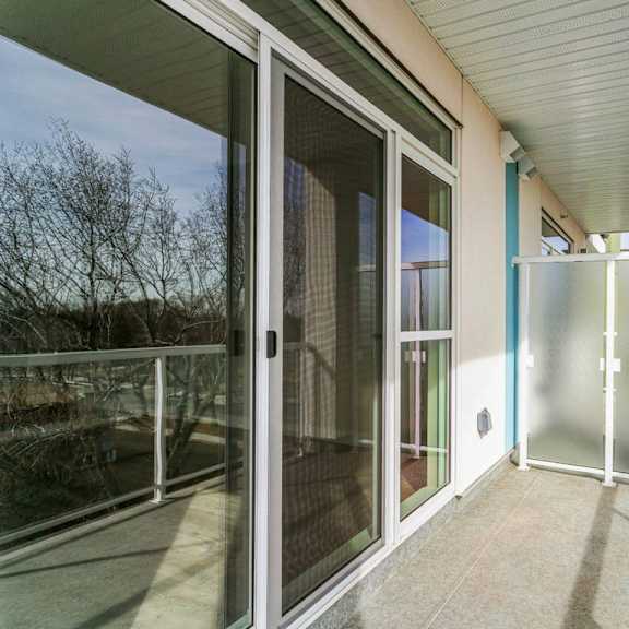 a balcony with a glass door and a white railing.