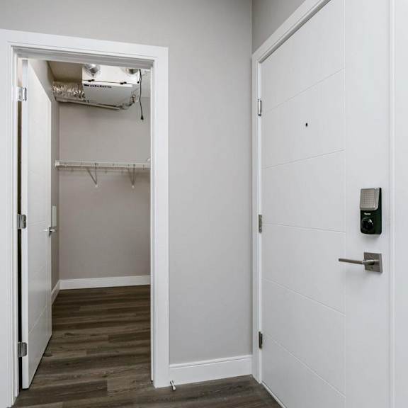 a white door is open to a room with a wood floor and a white wall.