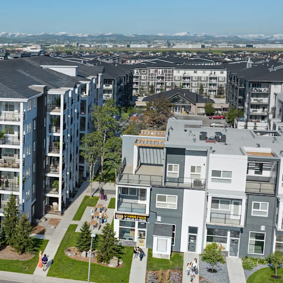 apartment buildings with green lawns and trees in front.