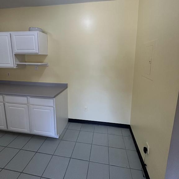 a bathroom with a white cabinet and a grey tiled wall.