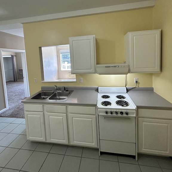 a kitchen with white cabinets and a window.