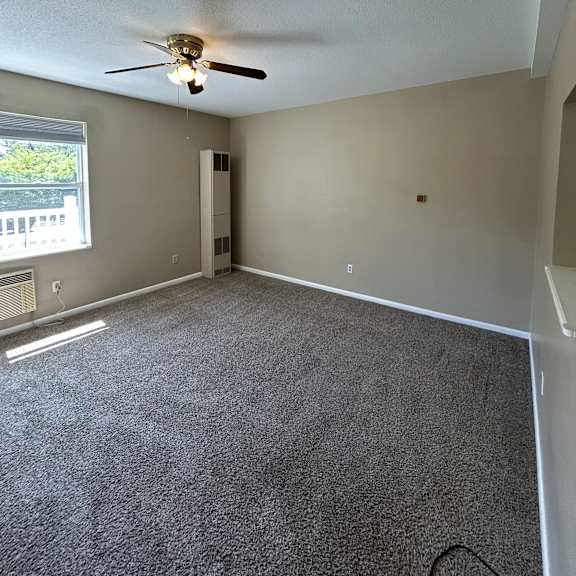 a ceiling fan is mounted on a white wall in a room with a window.