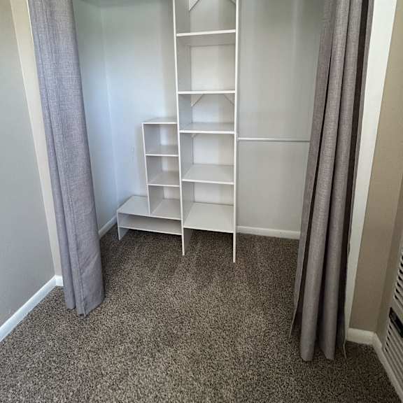 a white shelving unit with grey dividers is installed in a window.