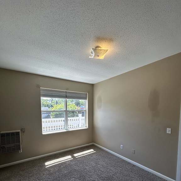 a wall with a light switch and a window with blinds.
