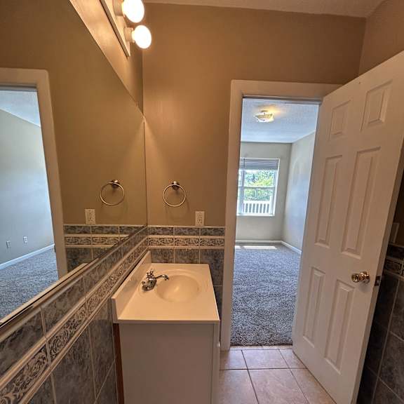 a bathroom with a window, a sink, and a mirror.