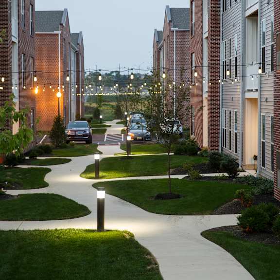 a long white pathway leads through a grassy area between two rows of red brick apartment buildings.