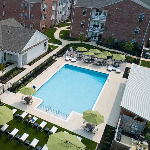 a large swimming pool surrounded by lawn chairs and umbrellas.