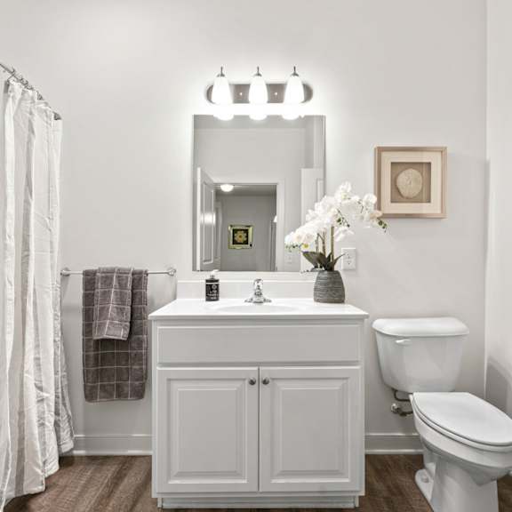 a white bathroom with a toilet, sink, and mirror.