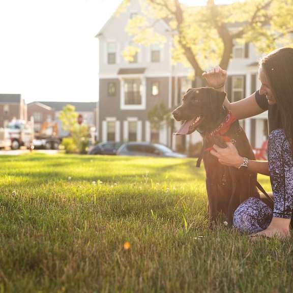 a woman is sitting on the grass with her dog.
