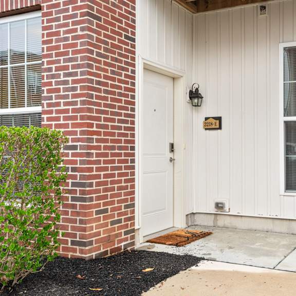 a white house with a brick pillar and a door with a number 123 on it.