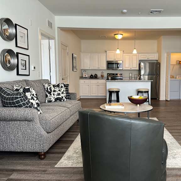 a modern living room with a grey couch and a black leather chair.