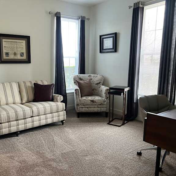 a living room with a striped couch, a chair, and two framed pictures on the wall.