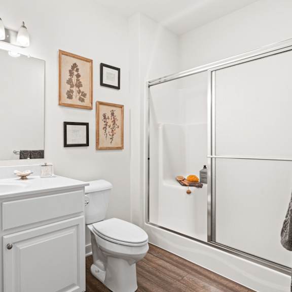 a white bathroom with a toilet, sink, and shower.