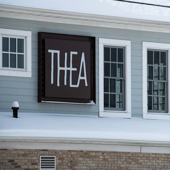a sign with the word "thea" is hanging on a building.