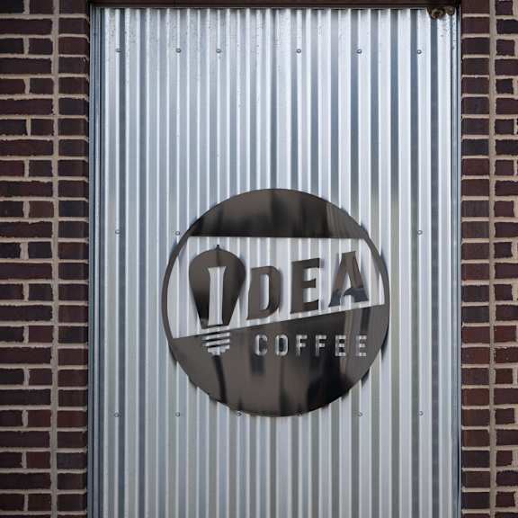 a sign for idea coffee is on a corrugated wall.