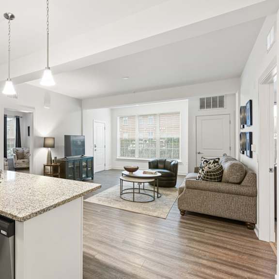 a modern kitchen with a granite countertop and a dining area with a couch.