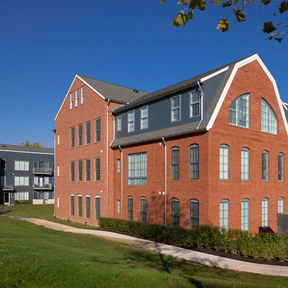 a red brick building with a black roof and a white building with a black roof in the background.