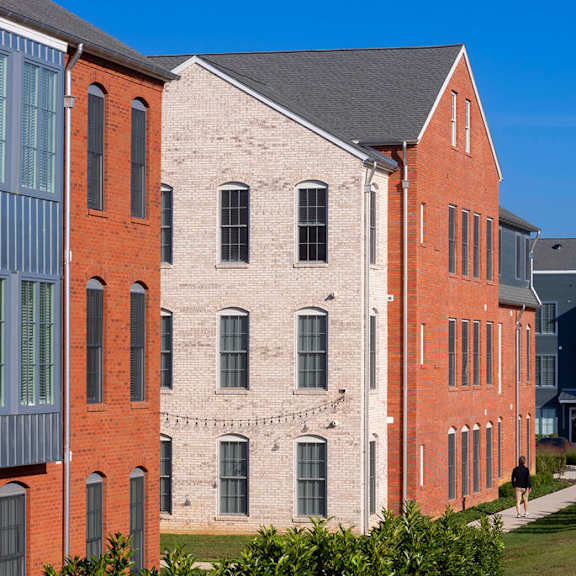 a red brick building with a black roof and a white building with a grey roof.