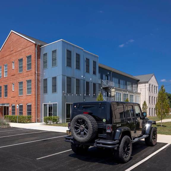 a black jeep is parked in a parking lot in front of a building.