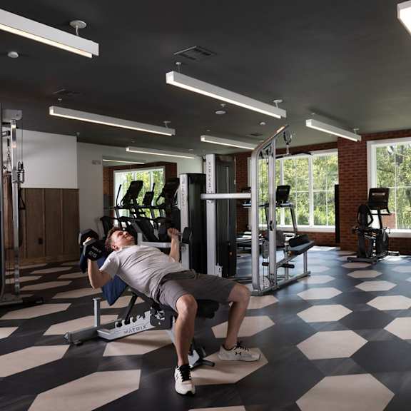 a man is working out in a gym with a checkered floor.