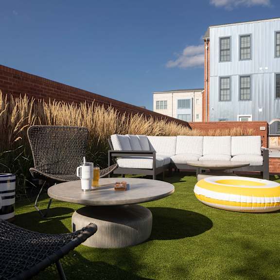 a patio with a table, chairs, and a couch with a building in the background.