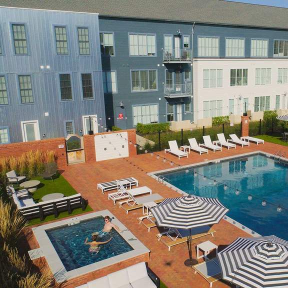 a large swimming pool surrounded by lounge chairs and umbrellas.