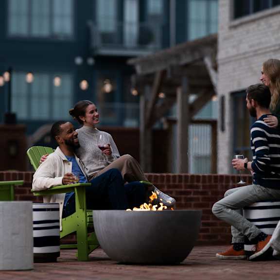 three people sitting around a fire pit on a patio.