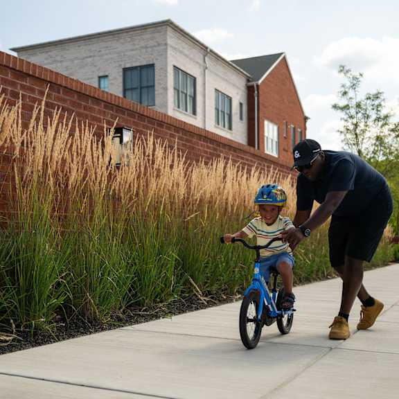 a man is teaching a young boy how to ride a bike.