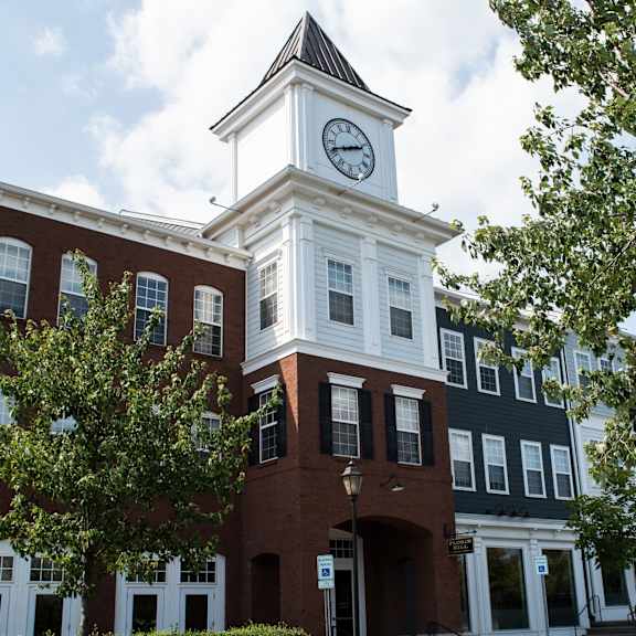 a white clock tower stands atop a red brick building.