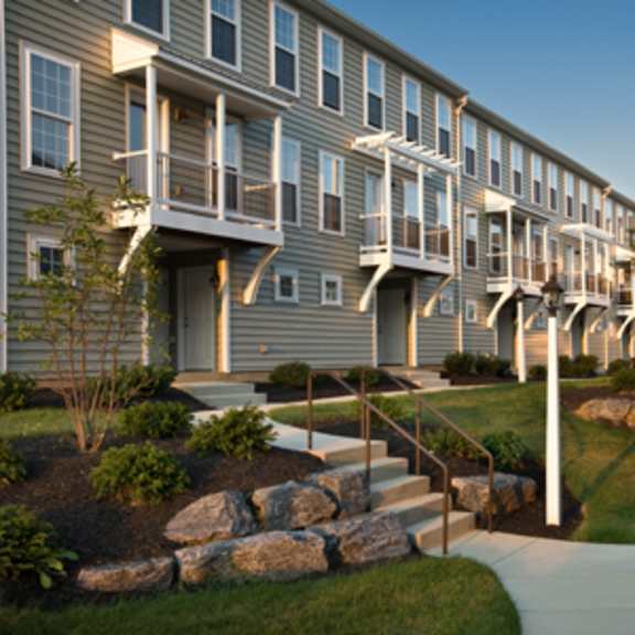 a row of apartment buildings with a stone wall and steps leading to the front doors.