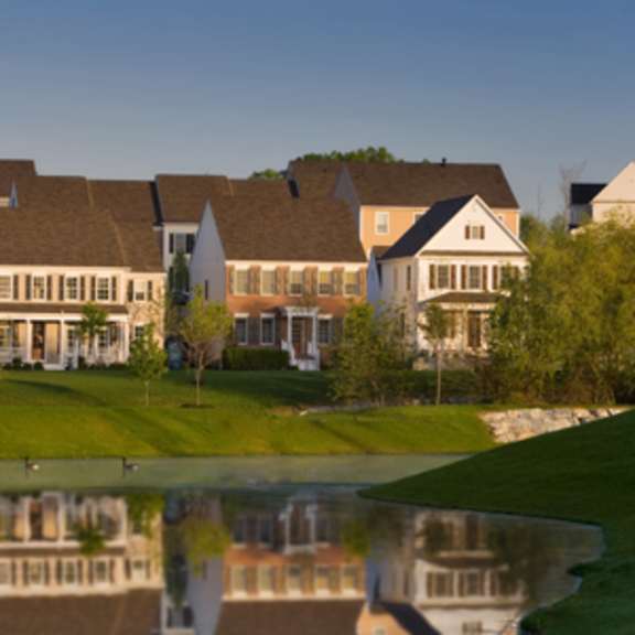 a serene lakeside view of a row of houses reflected in the water.