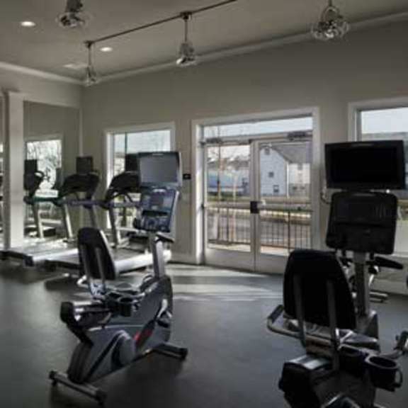 a gym with a variety of equipment including a leg press machine, a squat rack, and a bench press.