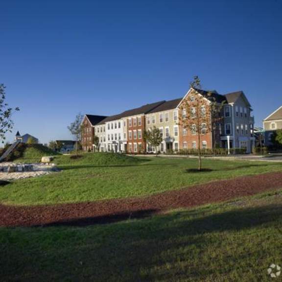 a large building with a clock tower is surrounded by a grassy area with a circular path.
