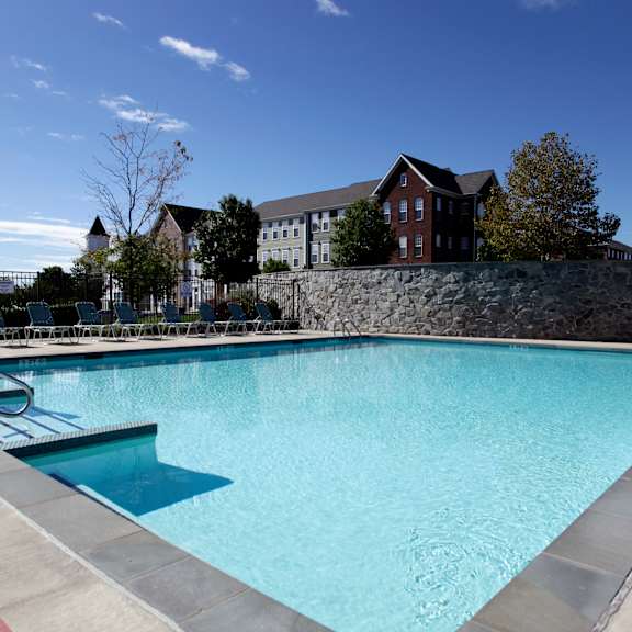 a swimming pool with a red line on the side and a stone wall in the background.