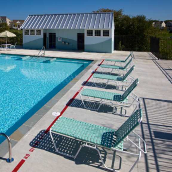 a large outdoor swimming pool with lounge chairs and a building in the background.