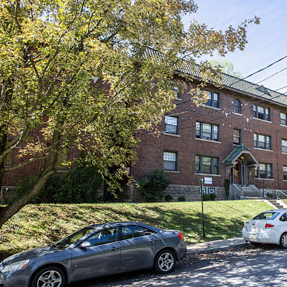 the exterior of a brick apartment building with cars parked in front