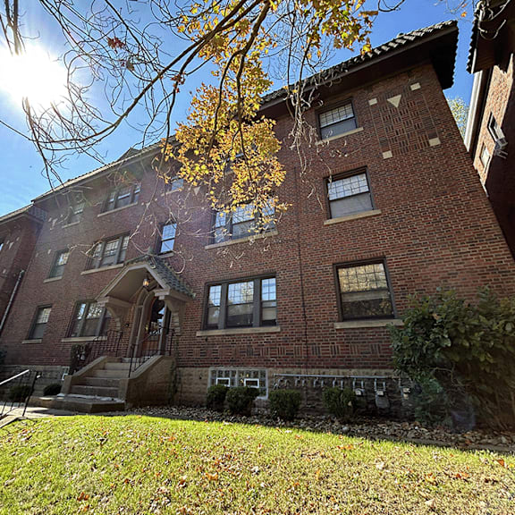 a red brick building with the sun shining in front of it