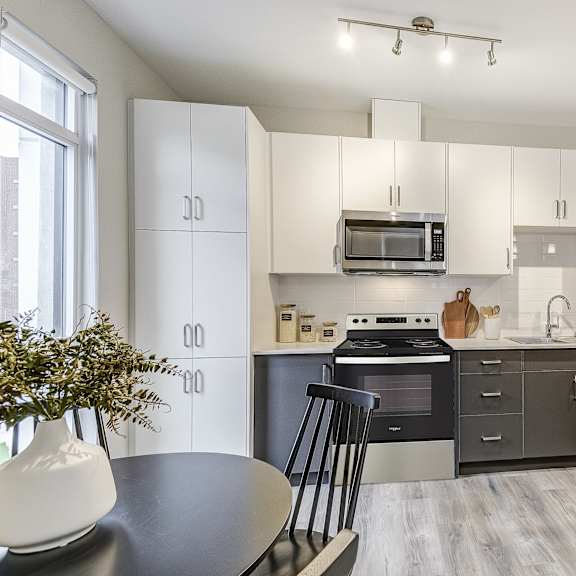 kitchen with white cabinets and black appliances and a table and chairs  at 101 base line road west, ontario