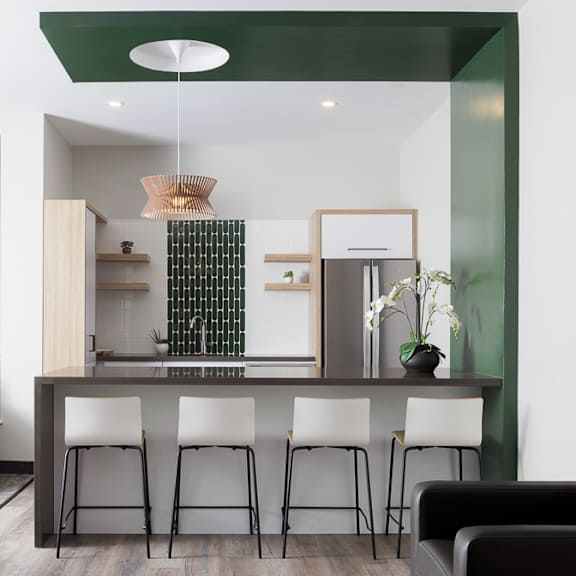 a modern kitchen with white and black furniture and a green accent wall.