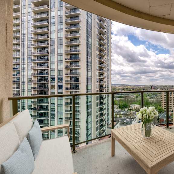a balcony with two chairs a table and a vase of flowers