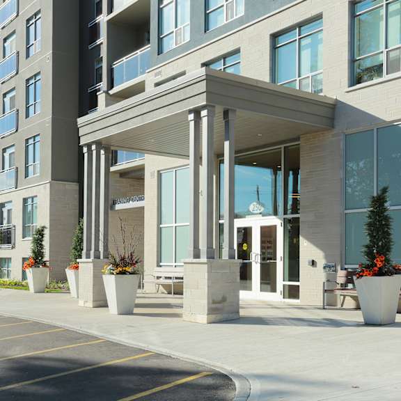 an entrance to an apartment building with potted plants on the sidewalk
