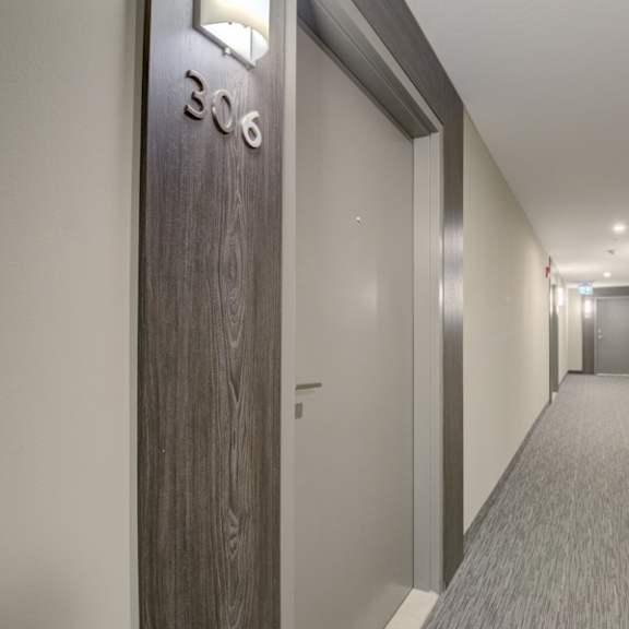 a hallway with a wooden door and a number on the wall