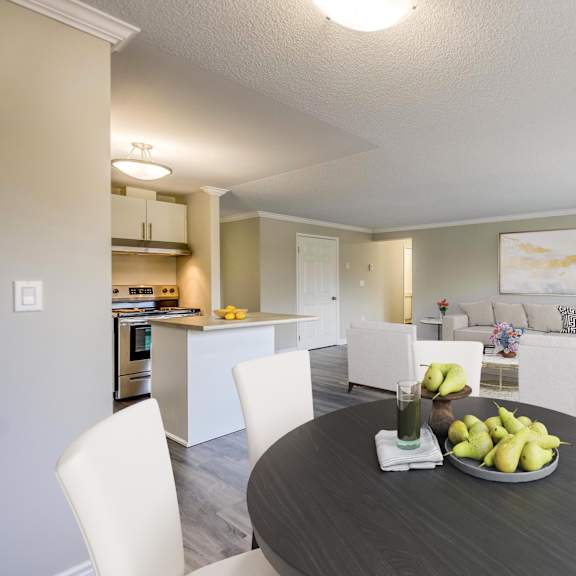 a dining area with a table and chairs and a kitchen in the background