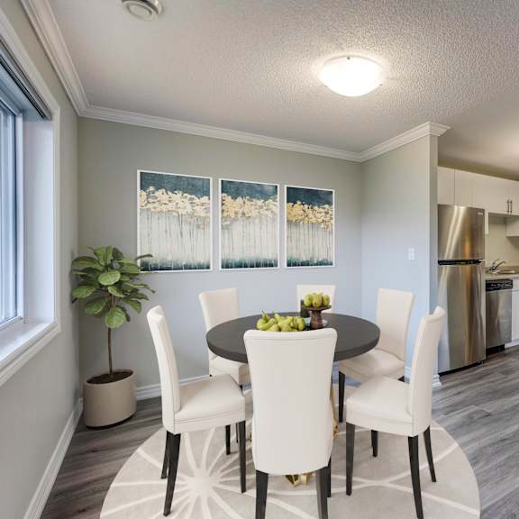 a dining area with a table and chairs and a kitchen in the background