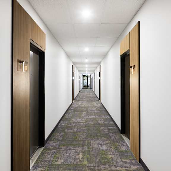 a long hallway with doors on both sides and a carpeted floor.