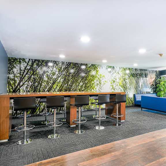 a room with a long table and chairs with a green planted wall behind it.