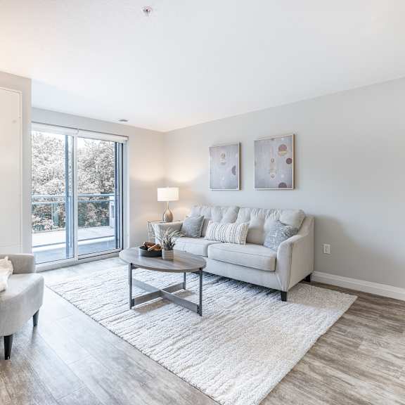a living room with a grey couch, a white chair, and a coffee table.