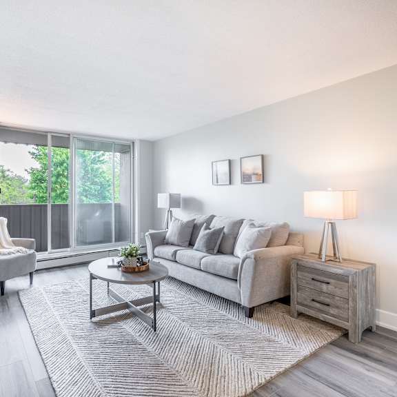 a living room with a grey couch, a coffee table, and a lamp  at platts crossing, london, on, n6h 4p4
