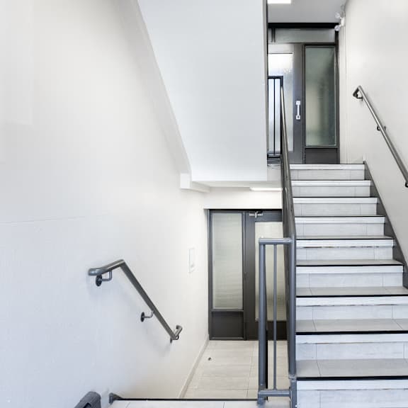 interior oakland staircase with a metal railing and a glass door at the top.